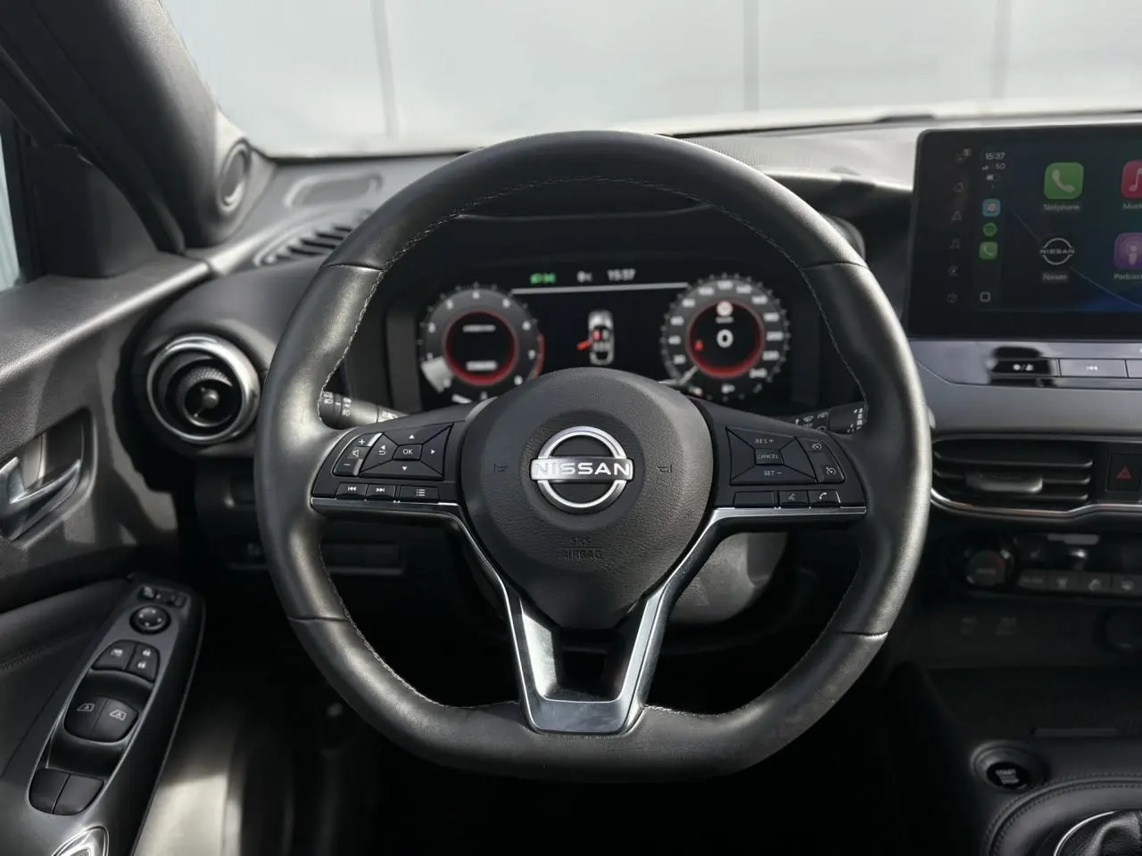 Vue rapprochée du volant en cuir noir du Nissan Juke 2025 avec tableau de bord digital et écran tactile.
