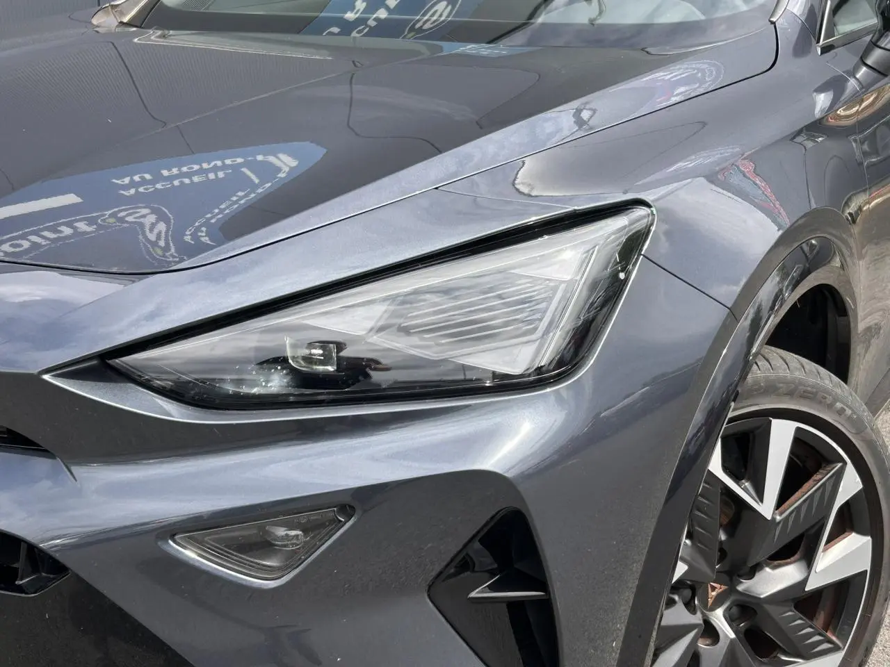 Gros plan sur l'avant droit du CUPRA Formentor gris magnétique, mettant en valeur le phare Tri-LED et la jante alliage 19 pouces.