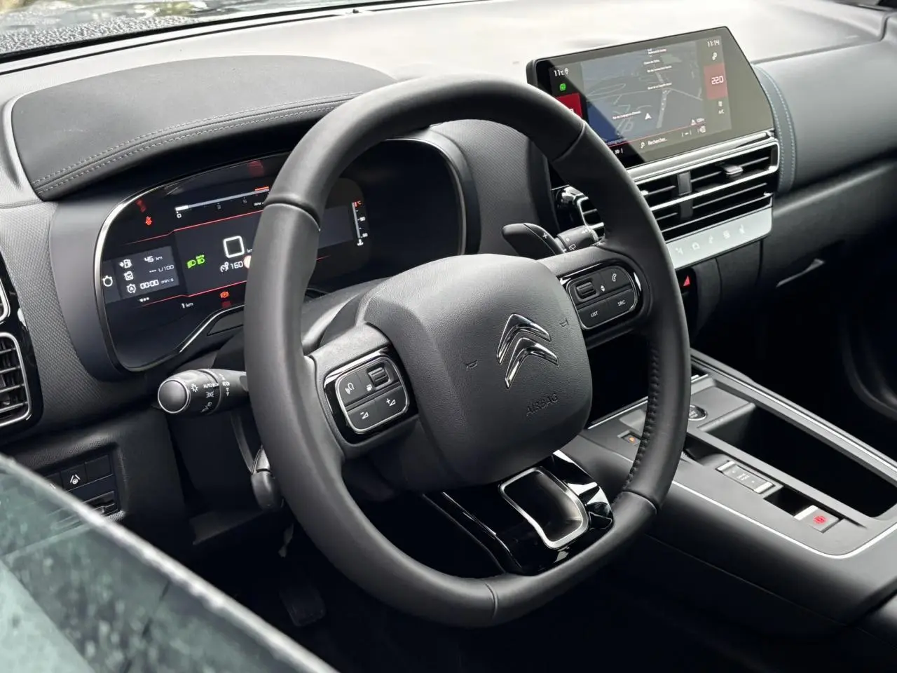 Vue intérieure du poste de conduite du Citroën C5 Aircross blanc, avec volant cuir et écran tactile central.