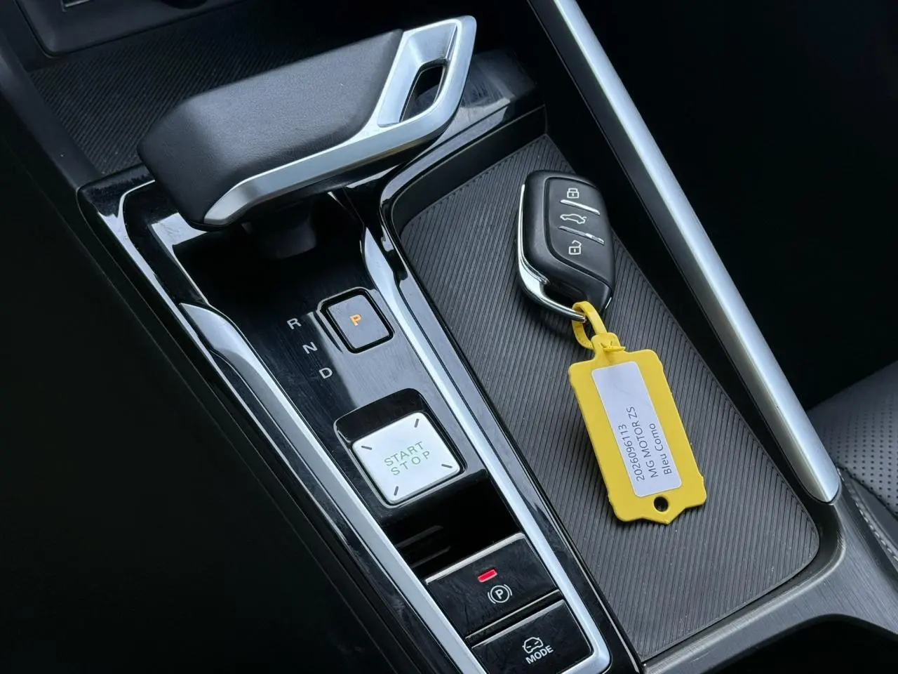 Gros plan sur la console centrale noire brillante du MG ZS Hybrid+ 2025 avec clé et levier de boîte automatique.