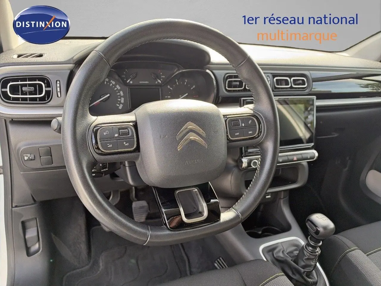 Intérieur de la Citroën C3 2021 vue du poste de conduite, volant cuir, tableau de bord noir et levier de vitesse manuel.