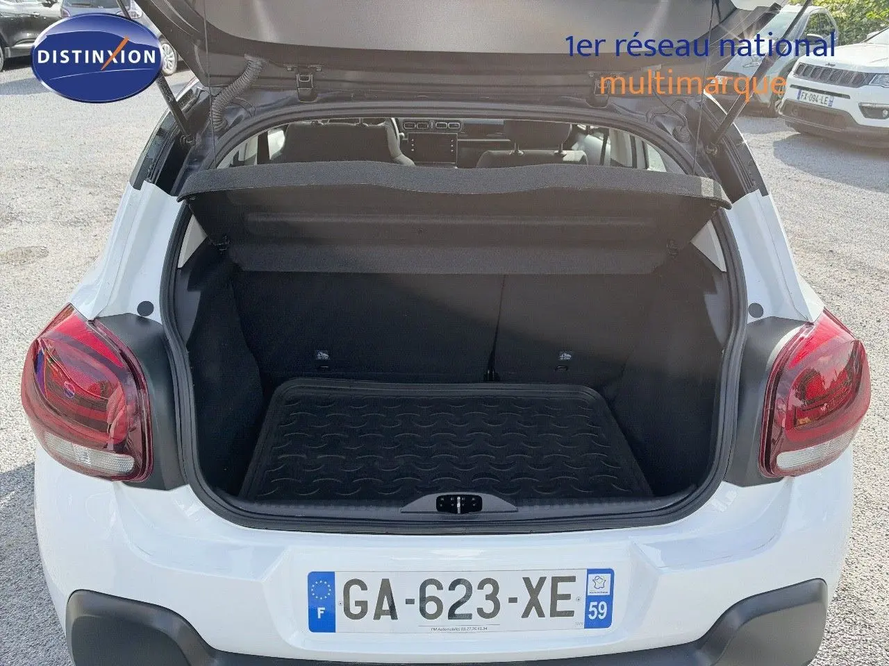 Coffre ouvert vu de l'arrière d'une Citroën C3 blanche de 2021 avec feux arrière rouges et plaque française.