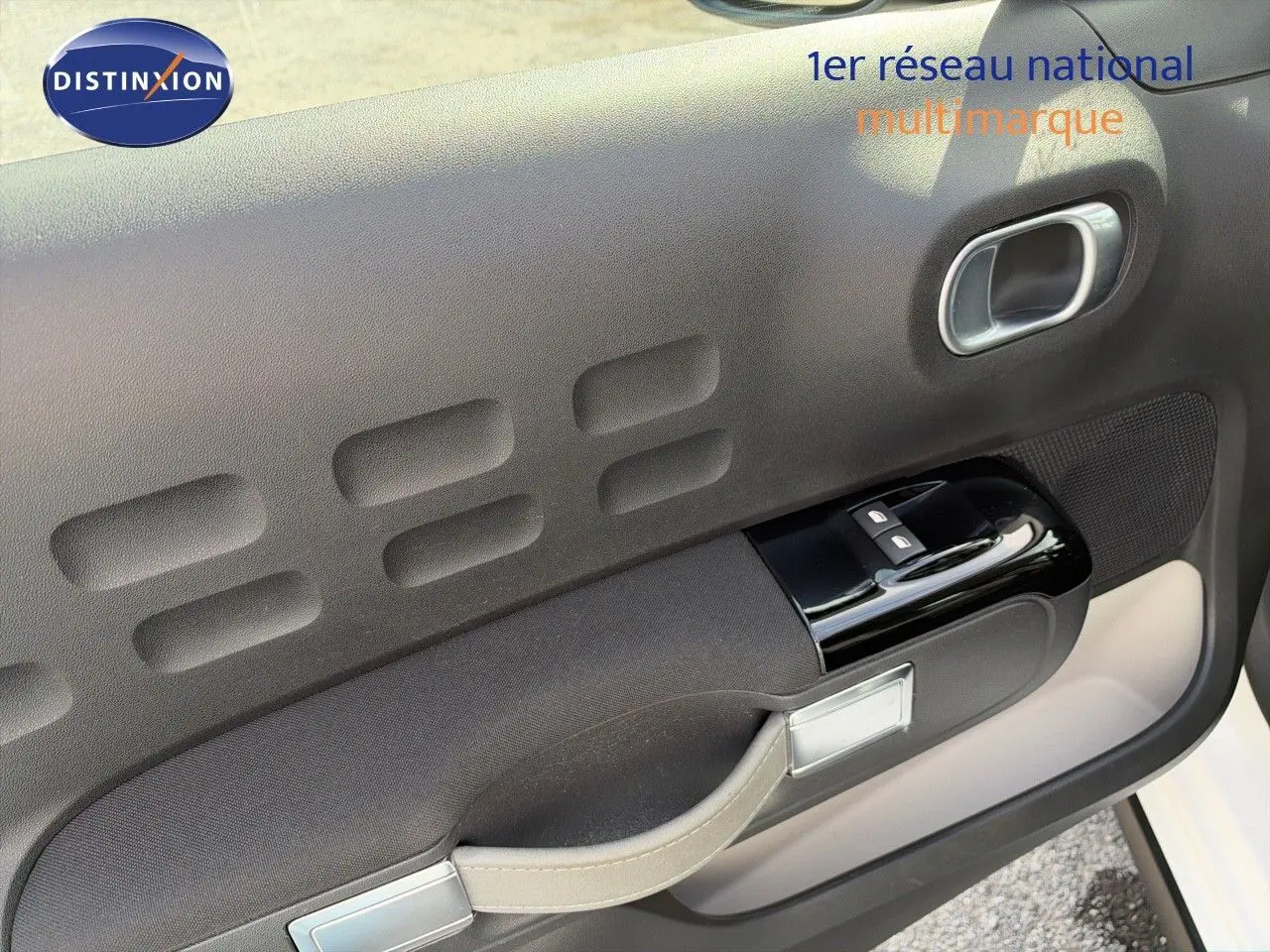Détail de la porte avant gauche de la Citroën C3 blanche 2021, avec commandes de vitres et poignée intégrée.