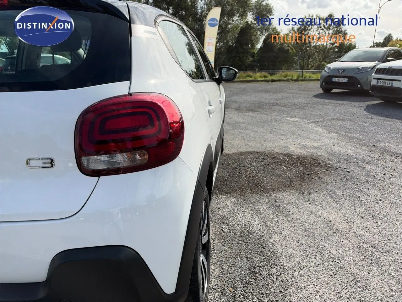 Vue 3/4 arrière droite d'une Citroën C3 blanche de 2021 avec feux arrière distinctifs et protections noires.