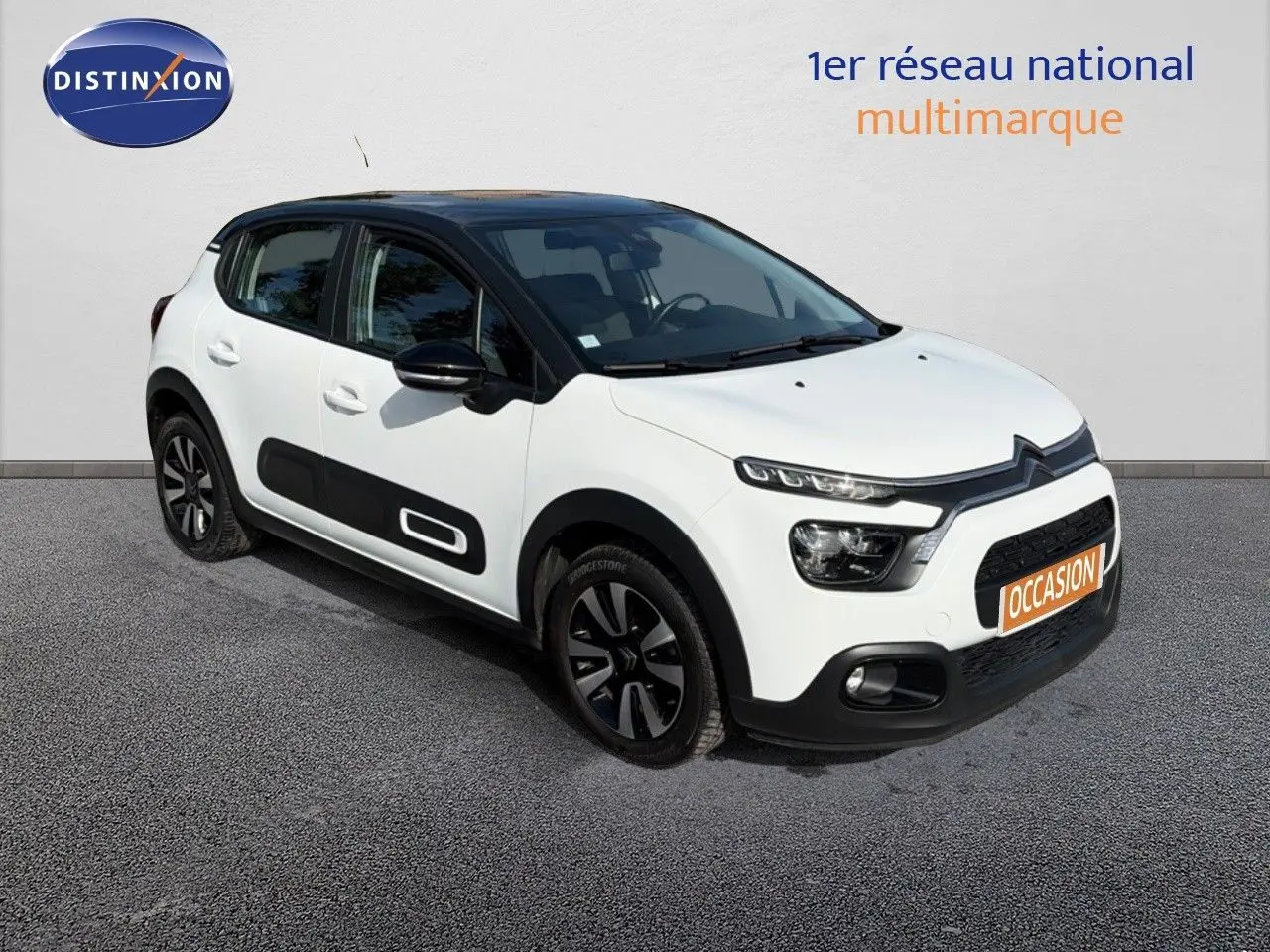 Citroën C3 blanche vue 3/4 avant droit, avec toit noir et protections latérales noires distinctives.