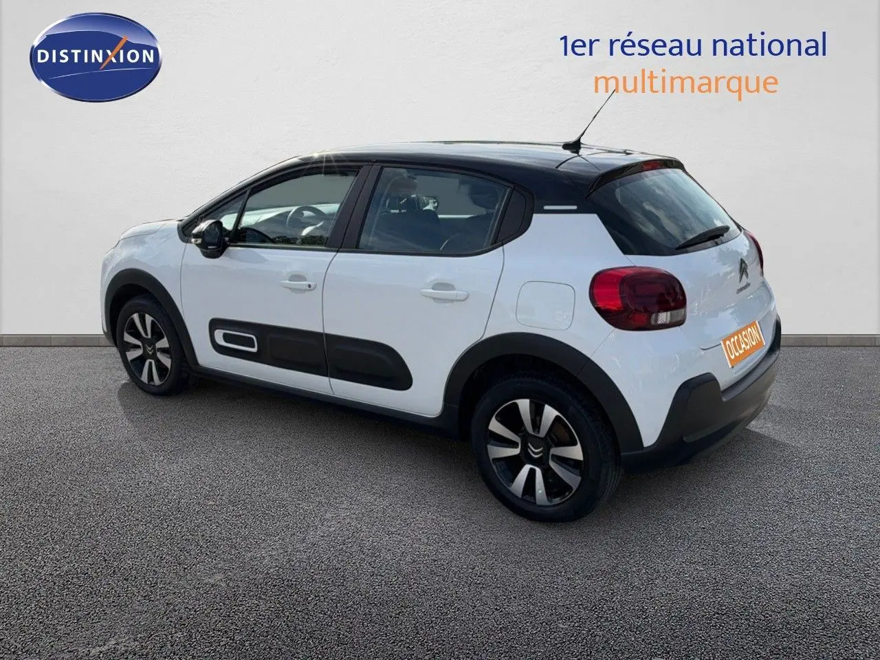 Citroën C3 blanche vue 3/4 arrière droit, toit noir et protections latérales noires distinctives.