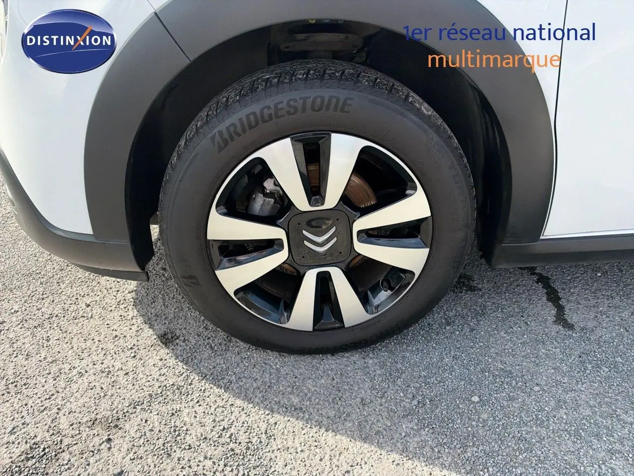 Gros plan sur la roue avant droite d'une Citroën C3 blanche de 2021 avec jante alliage bicolore et pneu Bridgestone.