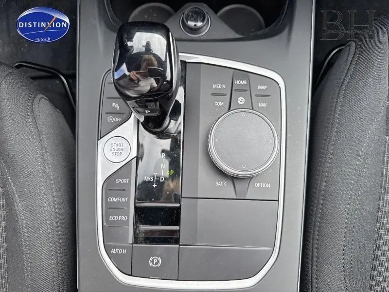 Gros plan sur la console centrale noire de la BMW Série 1 116dA avec levier de vitesses automatique et commandes multimédia.