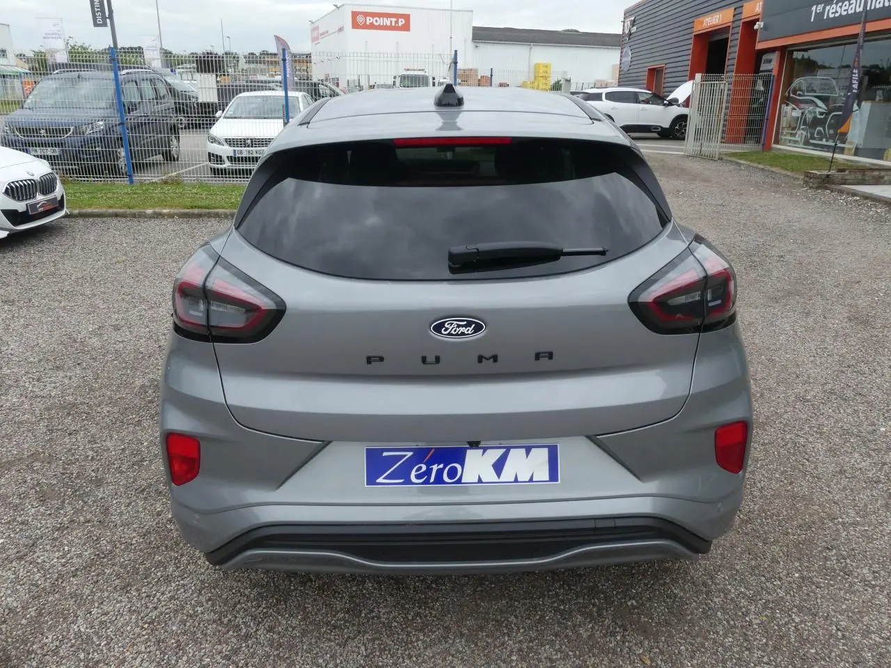 Vue arrière d'un Ford Puma gris métallisé 2025 avec feux LED et vitre arrière teintée sur parking.