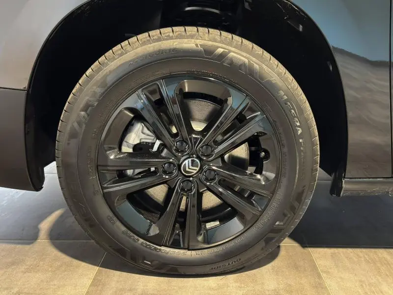 Gros plan sur la roue avant droite noire brillante du Citroën Berlingo Fourgon Noir Perla Nera nacré avec logo Citroën central.