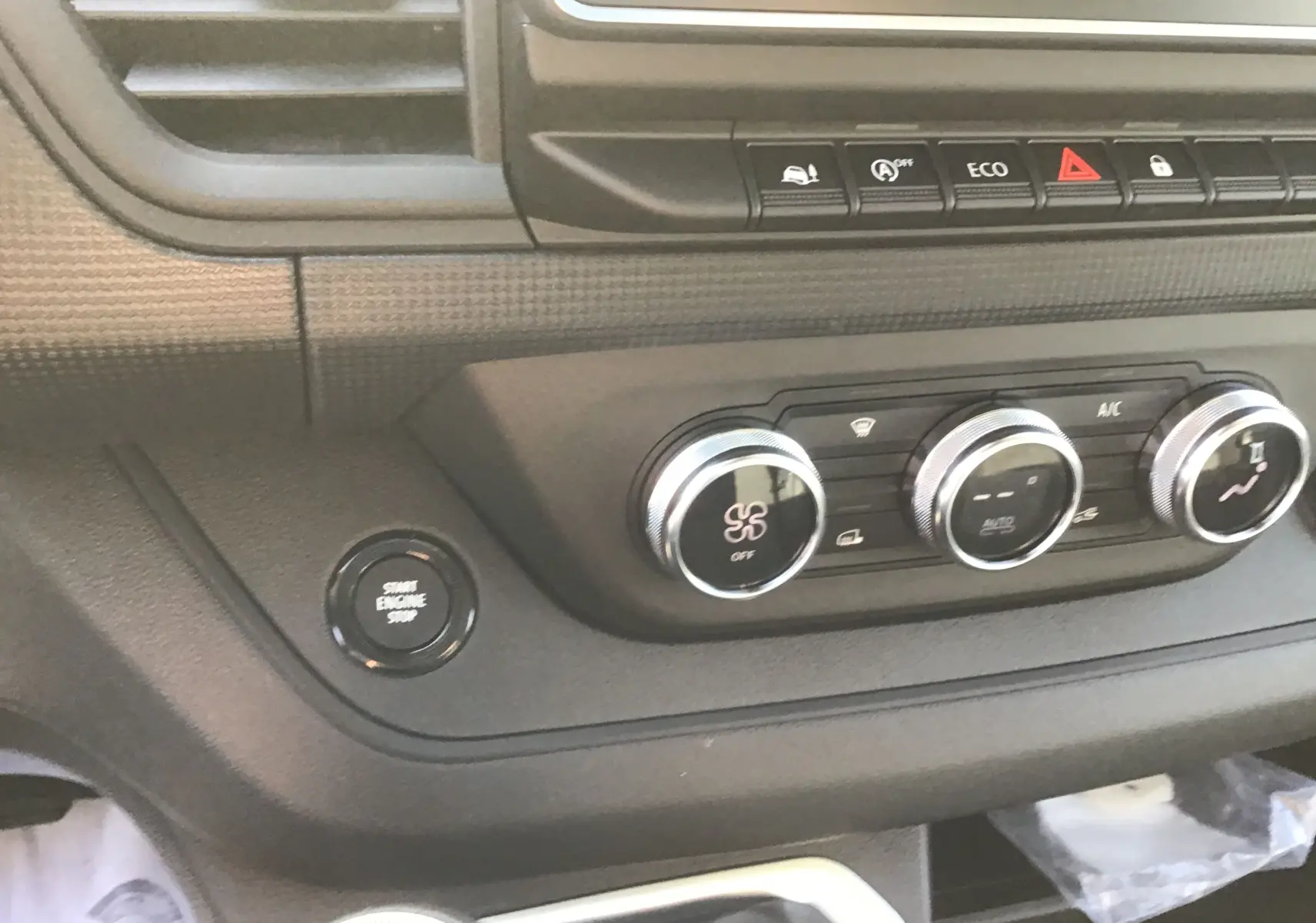 Détail du tableau de bord du Renault Trafic Fourgon blanc 2025 montrant les commandes de climatisation et le bouton start/stop.