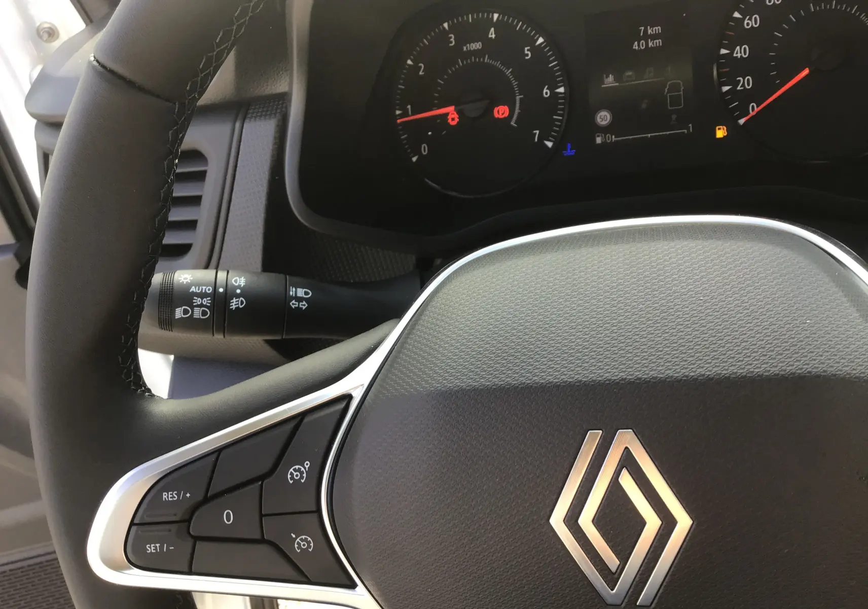 Gros plan sur le volant noir de Renault Trafic Fourgon blanc 2025 avec commandes au volant et tableau de bord partiel.