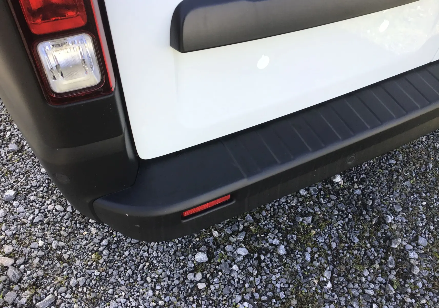 Gros plan sur l'angle arrière gauche du Renault Trafic Fourgon blanc, montrant le feu arrière et le pare-chocs noir.
