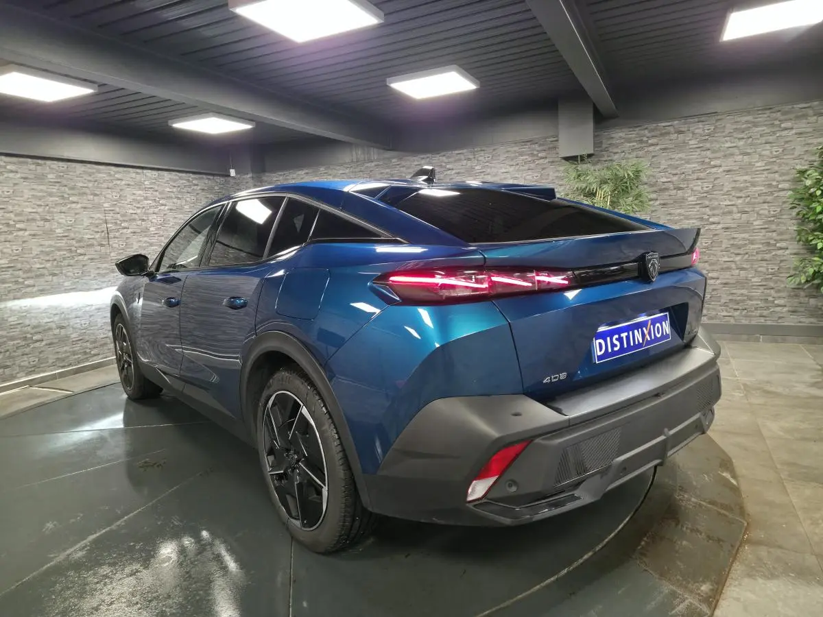 Vue 3/4 arrière droite d'une Peugeot 408 bleu métallisé avec feux arrière LED griffés et jantes alliage 19 pouces.