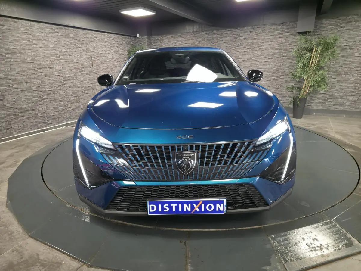 Vue avant d'une Peugeot 408 bleu métallisé avec calandre verticale et feux LED griffés allumés dans un showroom.