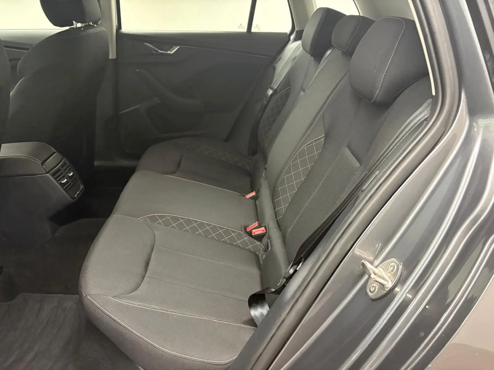 Vue intérieure côté droit des sièges arrière en tissu gris foncé avec surpiqûres, portière ouverte du Skoda Kamiq Gris Graphite 2023.