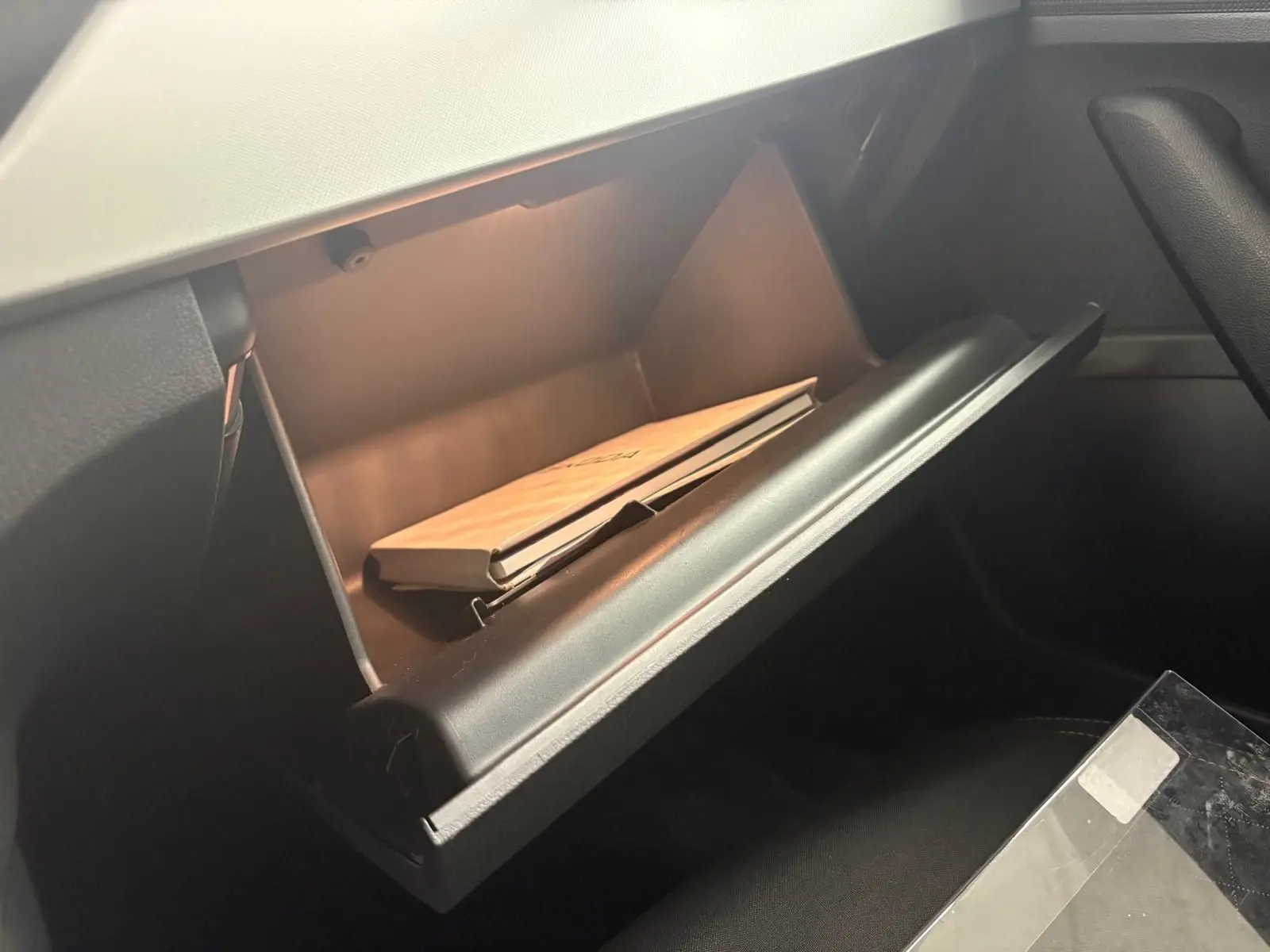 Boîte à gants ouverte côté passager dans un Skoda Kamiq 2023 gris graphite avec manuel à l’intérieur.