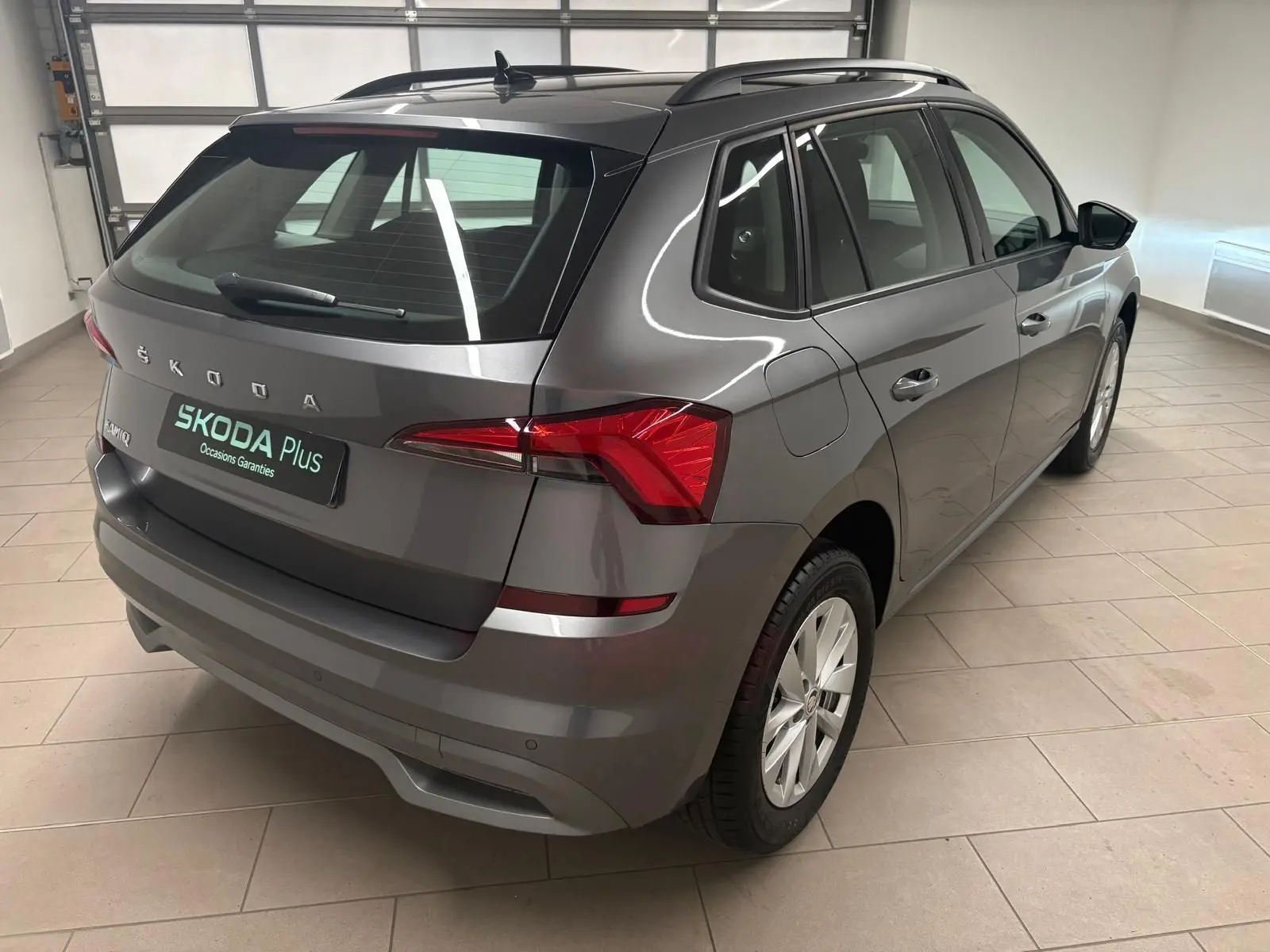 Vue 3/4 arrière droite d'un Skoda Kamiq 2023 gris graphite métallisé, avec feux arrière LED et jantes alliage.