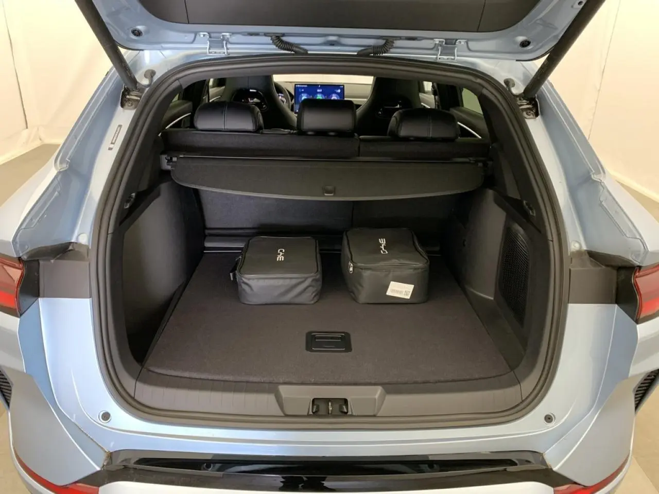 Coffre ouvert vu de l'arrière du BYD SEAL U 1.5 DM-i 2025 en bleu Tian Qing avec deux sacs de rangement noirs.