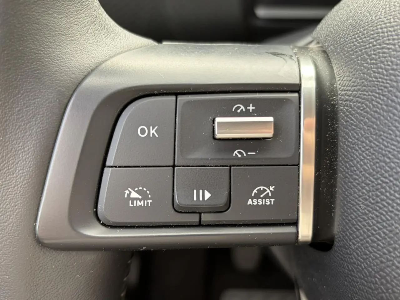 Gros plan sur les commandes de régulateur de vitesse au volant côté gauche d'une Citroën C4 2024 Rouge Elixir.