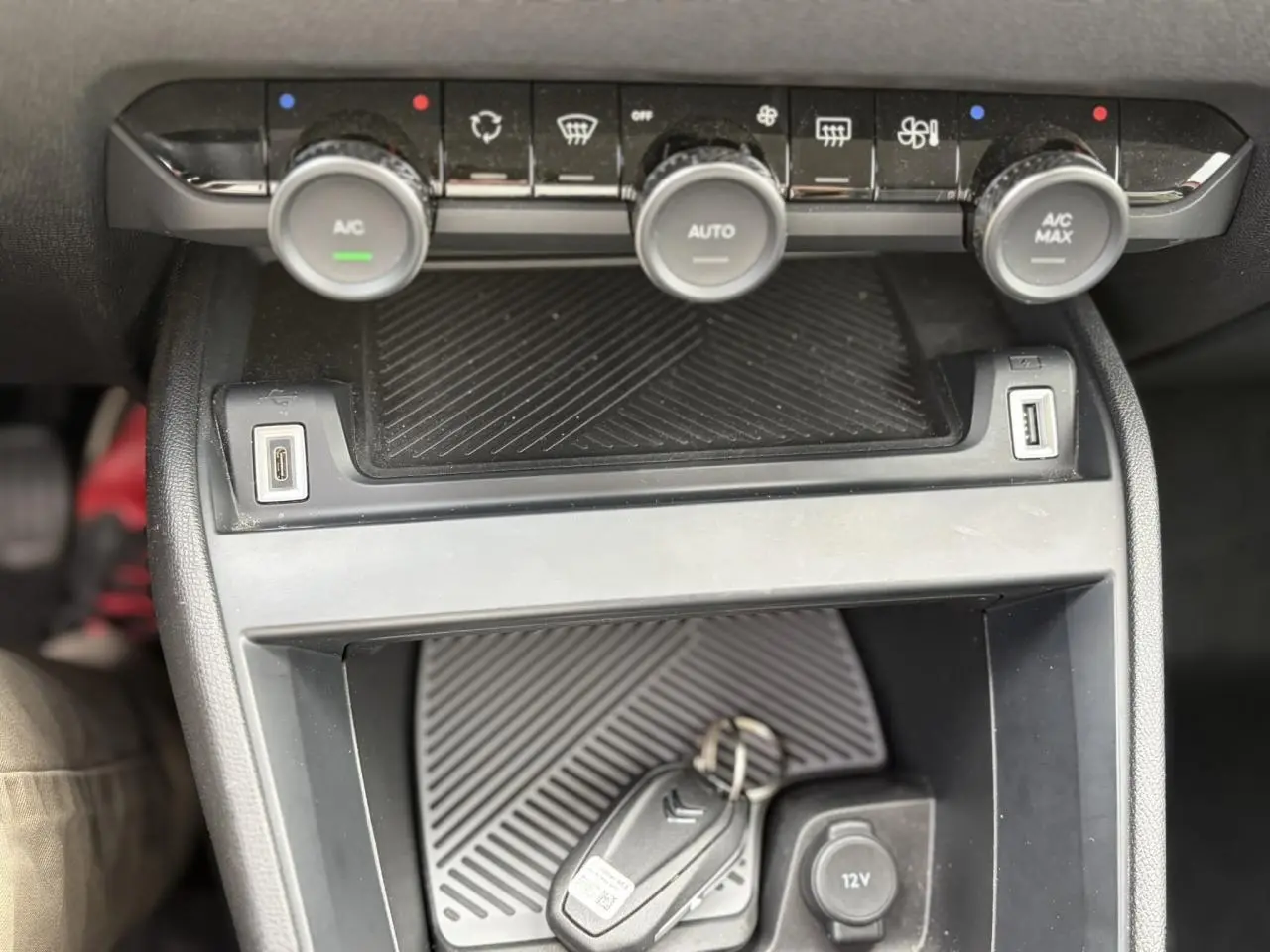Vue rapprochée de la console centrale noire de la Citroën C4 avec commandes climatisation et clé posée.