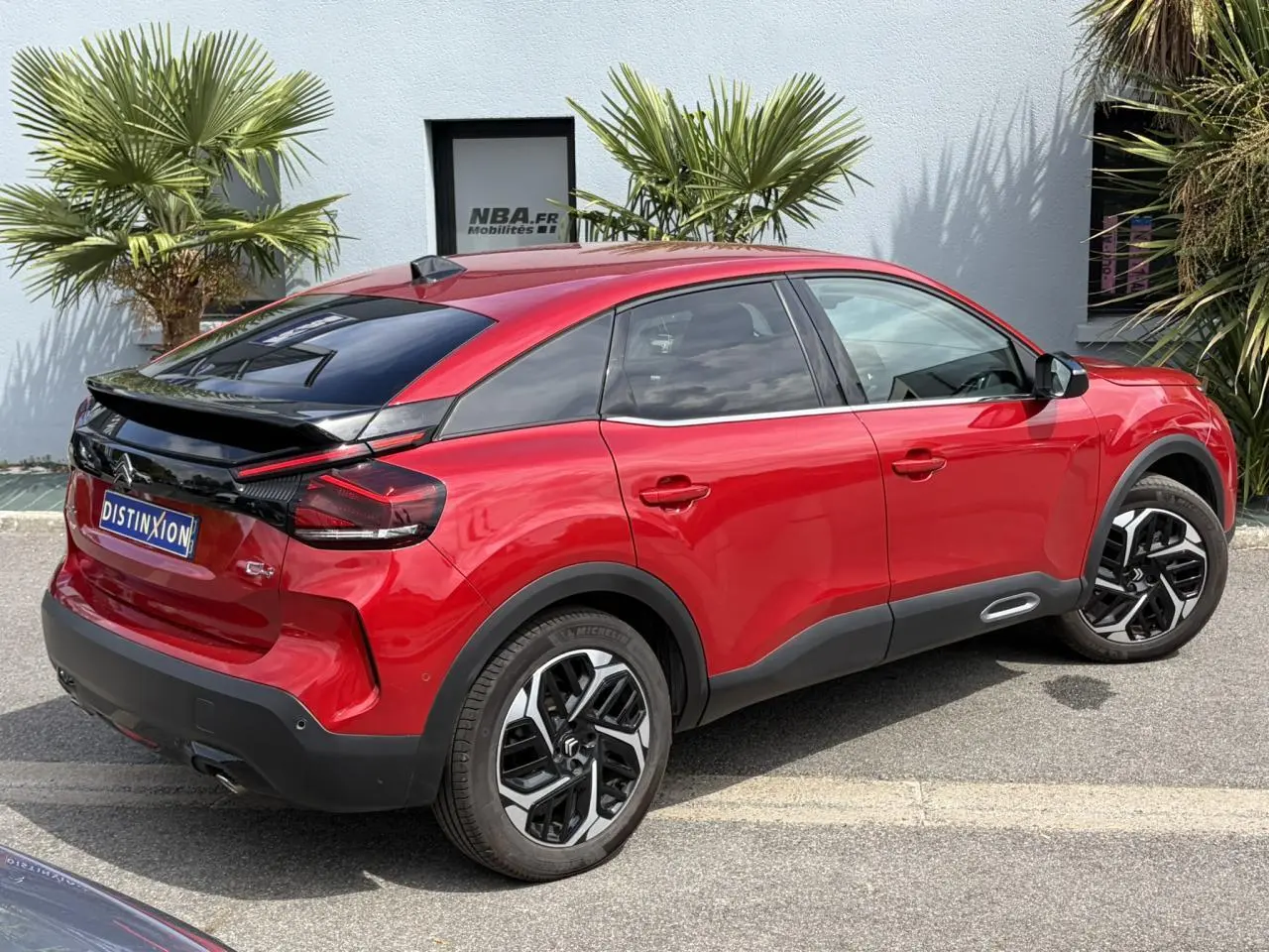 Vue 3/4 arrière droite d'une Citroën C4 2024 Rouge Elixir avec jantes alliage 18'' et toit noir contrasté.
