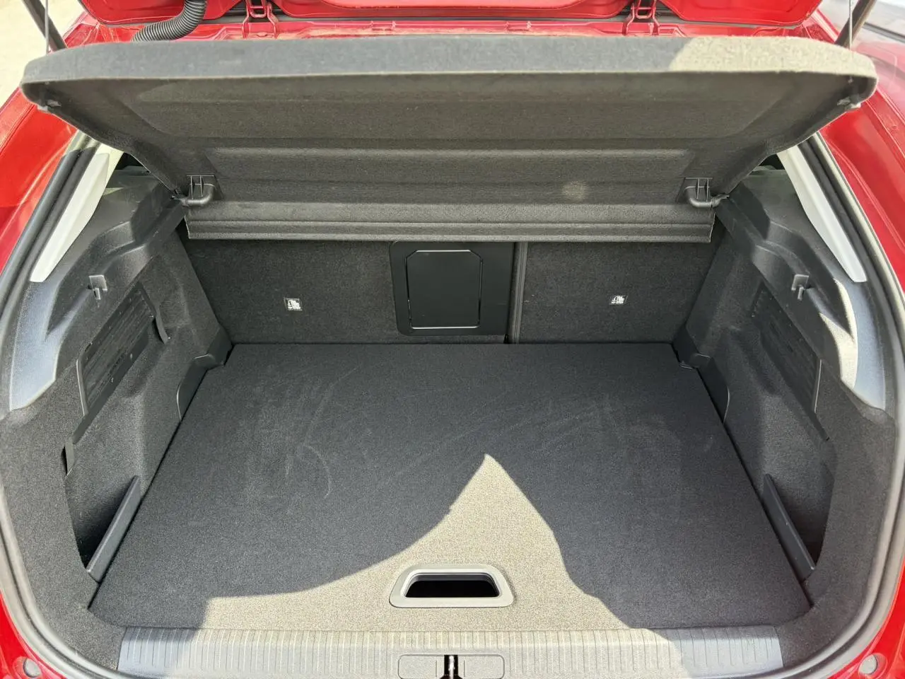 Coffre ouvert vu de l'arrière d'une Citroën C4 Rouge Elixir, montrant un espace de chargement propre et modulable.