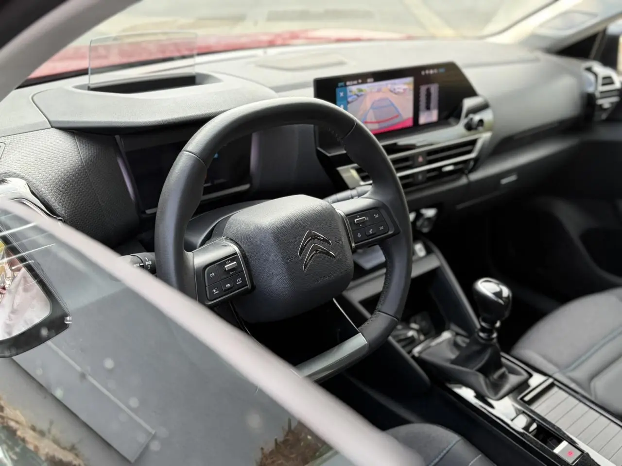 Vue intérieure côté conducteur de la Citroën C4 1.2 PureTech 130 Max avec volant cuir, écran tactile et levier de vitesse manuel.