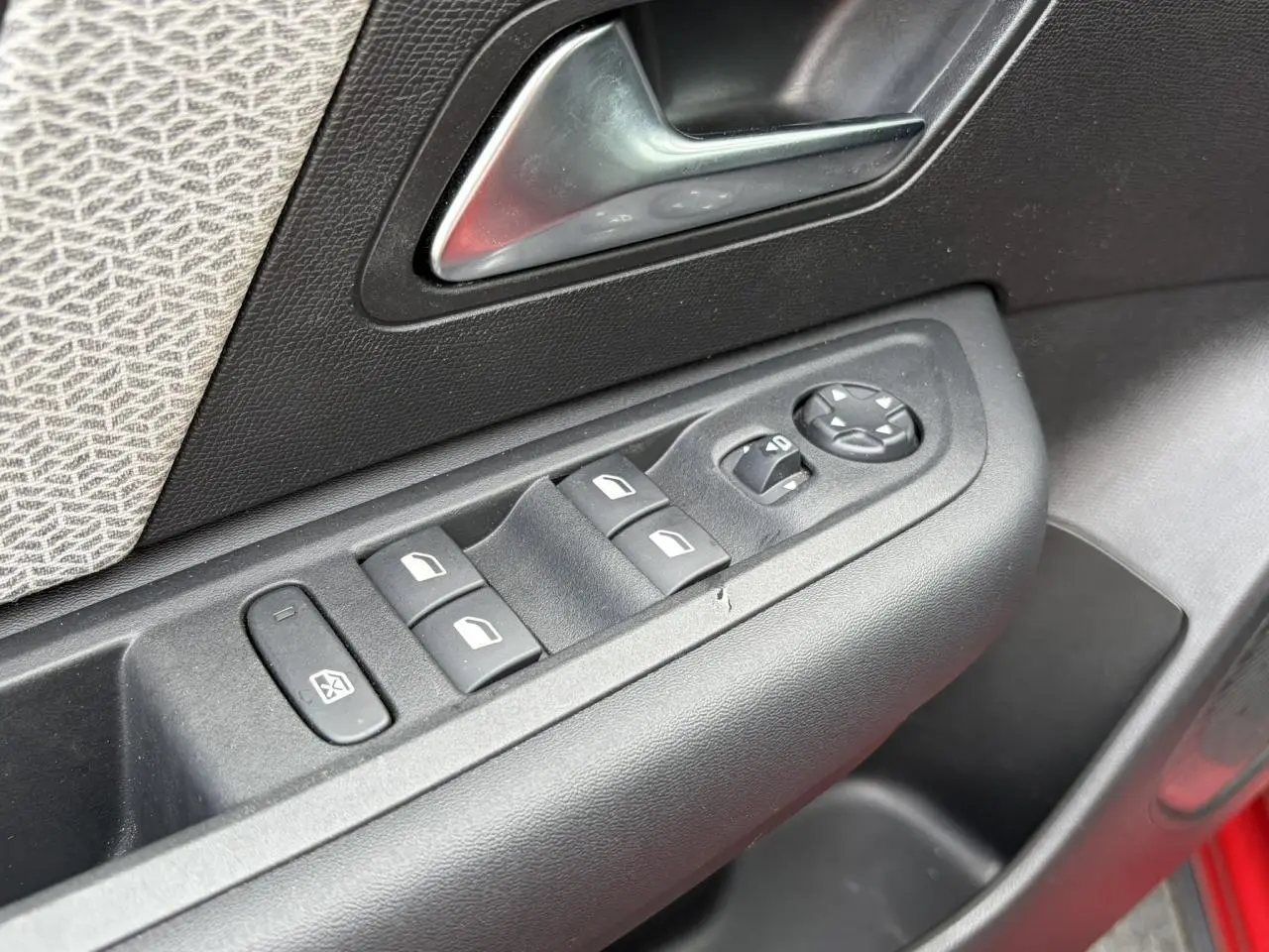 Détail des commandes de lève-vitres et rétroviseurs sur la porte côté conducteur d'une Citroën C4 Rouge Elixir.