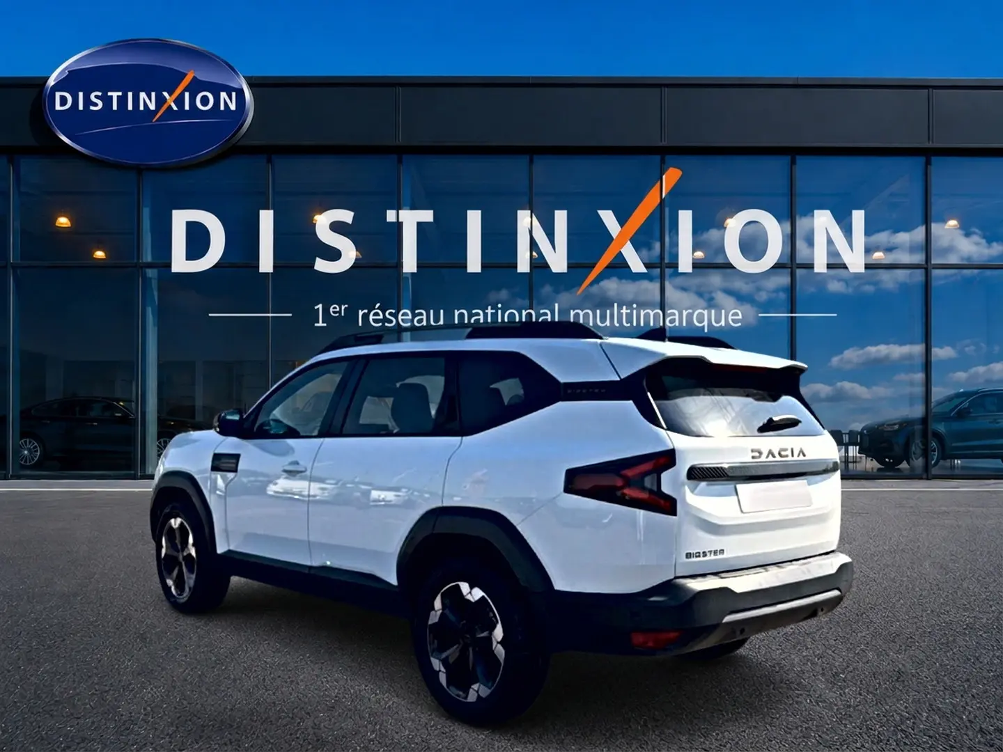 SUV Dacia Bigster blanc vu en 3/4 arrière droit, avec barres de toit et jantes alu noires.