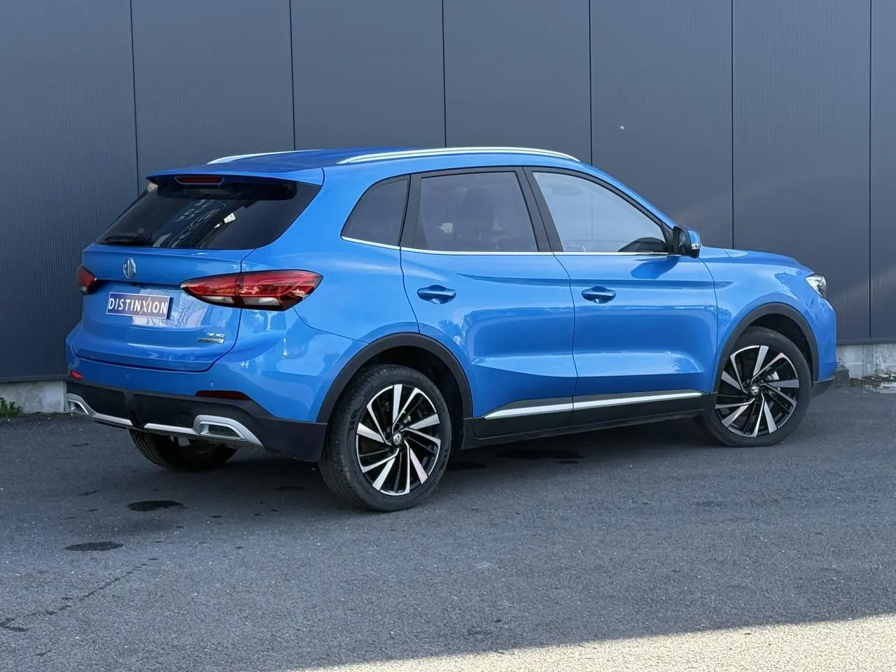 Vue 3/4 arrière droite du MG ZS 1.5 Hybrid+ 197 Luxury bleu Como avec jantes alliage 18 pouces et feux LED.
