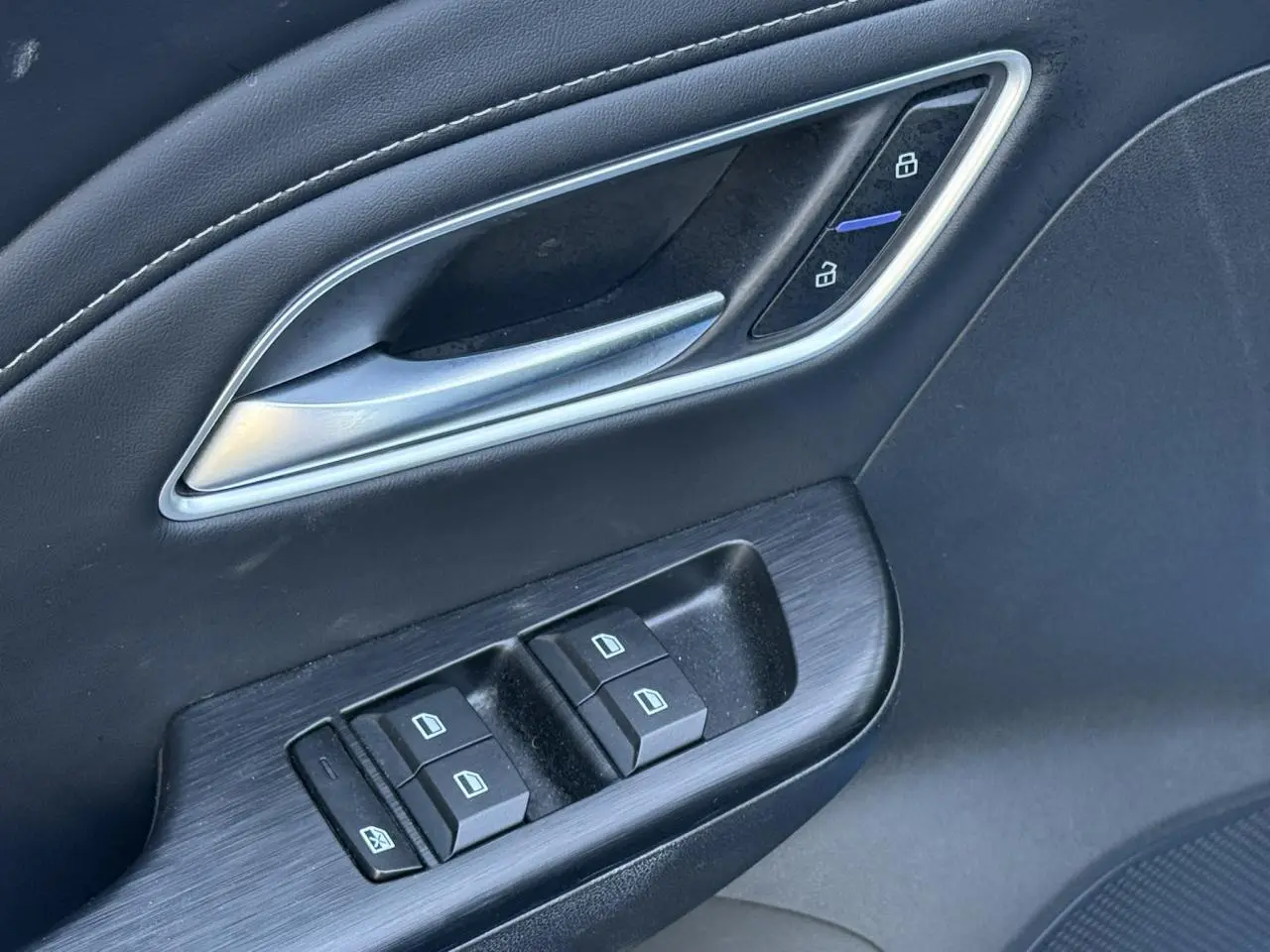 Gros plan sur la porte côté conducteur du MG ZS 1.5 Hybrid+ 197 Luxury avec commandes de vitres et verrouillage en similicuir noir.