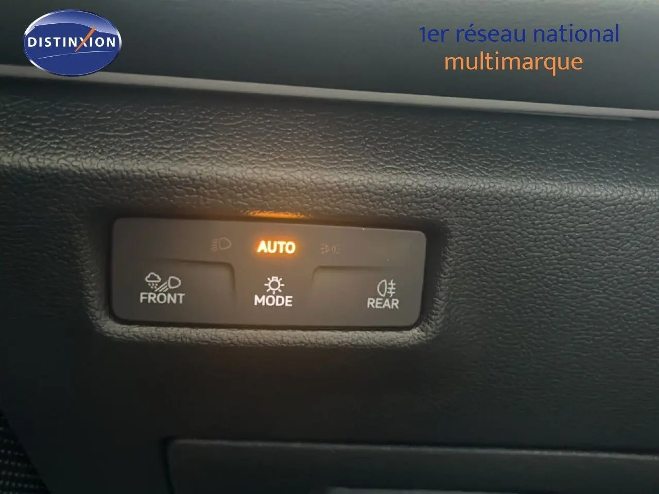 Détail du tableau de bord du Volkswagen Tiguan 2026, montrant les commandes d'éclairage en mode automatique avec rétroéclairage orange.