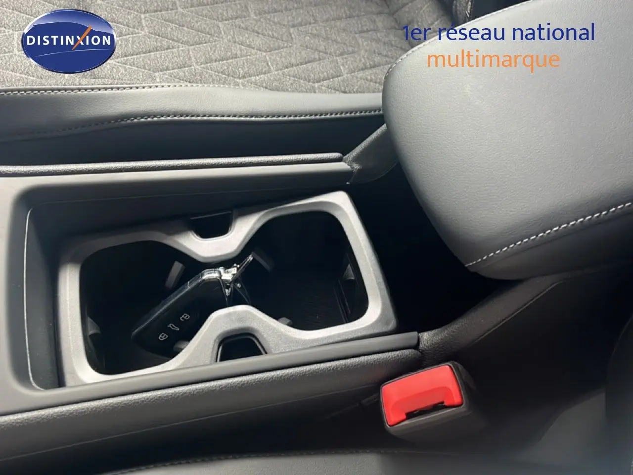 Gros plan intérieur sur le porte-gobelets central avec clé Volkswagen, sellerie cuir noir et accoudoir visible.