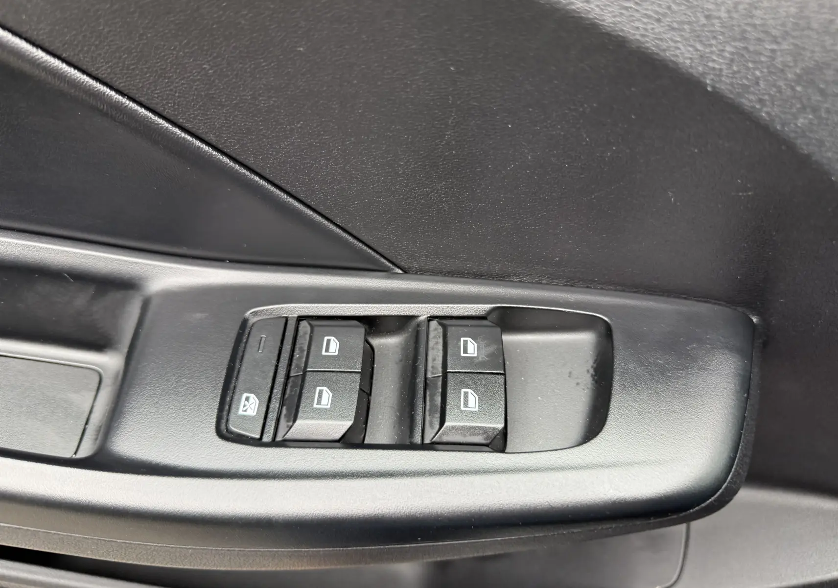 Gros plan sur les commandes de lève-vitres côté conducteur en plastique noir du MG3 1.5 HYBRID+ 195 LUXURY Pebble Black 2025.