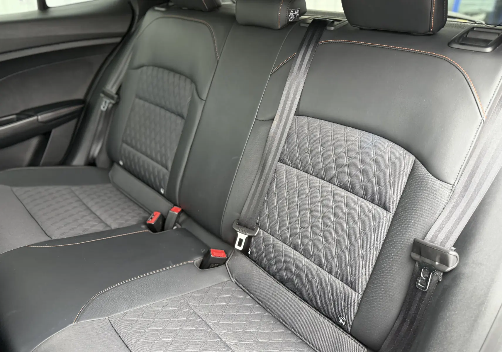 Vue intérieure des sièges arrière en cuir noir avec surpiqûres orange du MG3 1.5 HYBRID+ 195 LUXURY 2025.