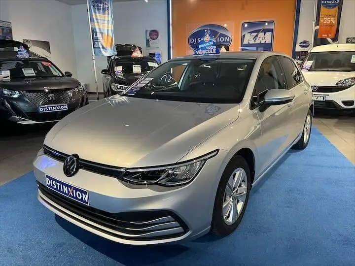 Volkswagen Golf 8 1.0 E TSI 110 CH DSG7 en reflet d'argent métal vue 3/4 avant dans un showroom.