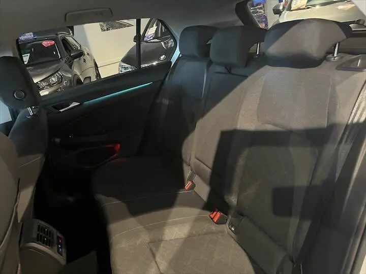 Vue intérieure arrière de la Volkswagen Golf 8 en tissu noir, montrant les sièges et appuie-têtes arrière.