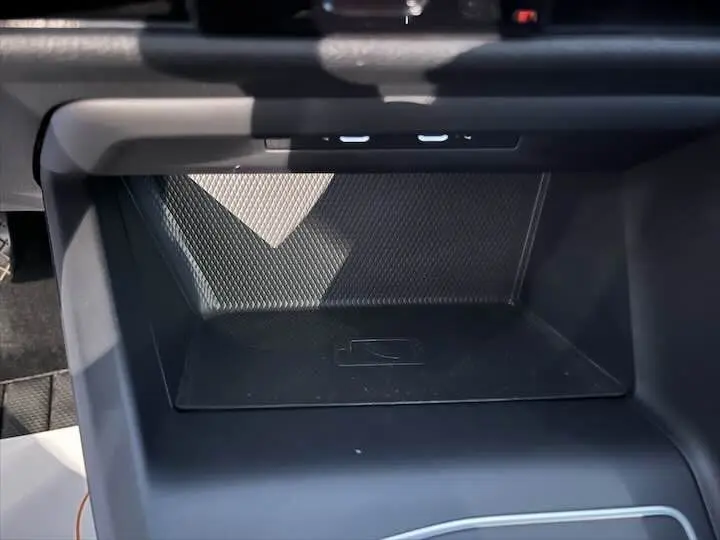 Espace de rangement intérieur noir de la Volkswagen Golf 8 1.0 E TSI 110 CH DSG7 avec surface texturée et symbole de recharge sans fil.