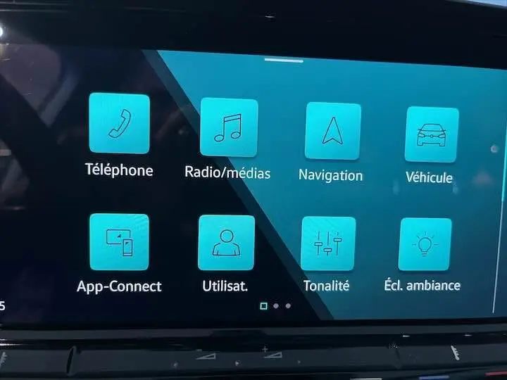 Écran tactile central de la Volkswagen Golf 8 en mode menu principal avec icônes bleues sur fond noir.