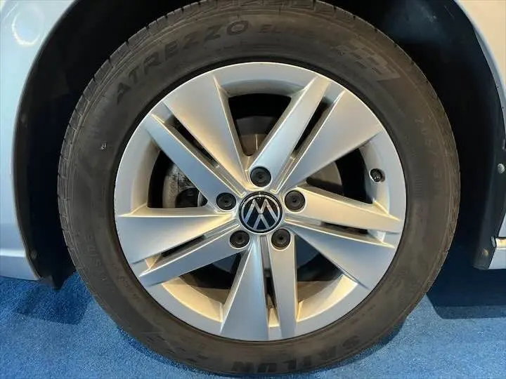 Gros plan sur la roue avant gauche argentée d'une Volkswagen Golf 8 1.0 E TSI 110 CH DSG7 reflet d'argent métal.