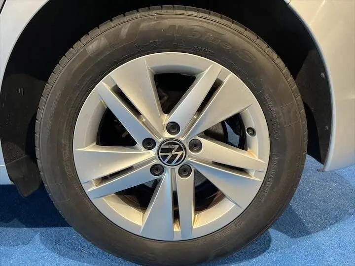 Gros plan sur la jante argentée à 5 doubles branches de la Volkswagen Golf 8 en reflet d'argent métal.