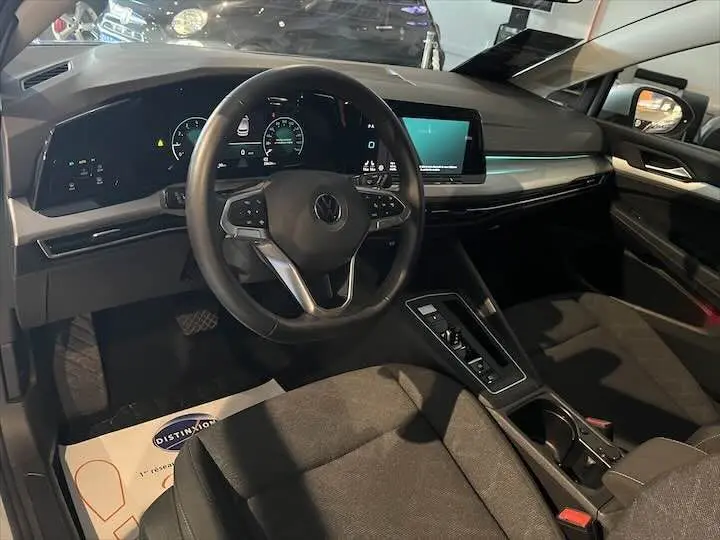 Intérieur de Volkswagen Golf 8 essence, vue du poste de conduite avec tableau de bord numérique et écran central tactile.