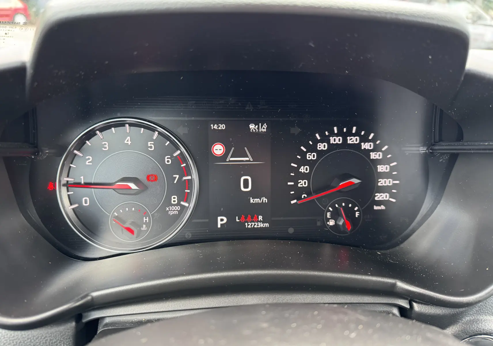 Vue rapprochée du tableau de bord numérique de la Suzuki Swift bleu, affichant compte-tours, vitesse et jauge de carburant.