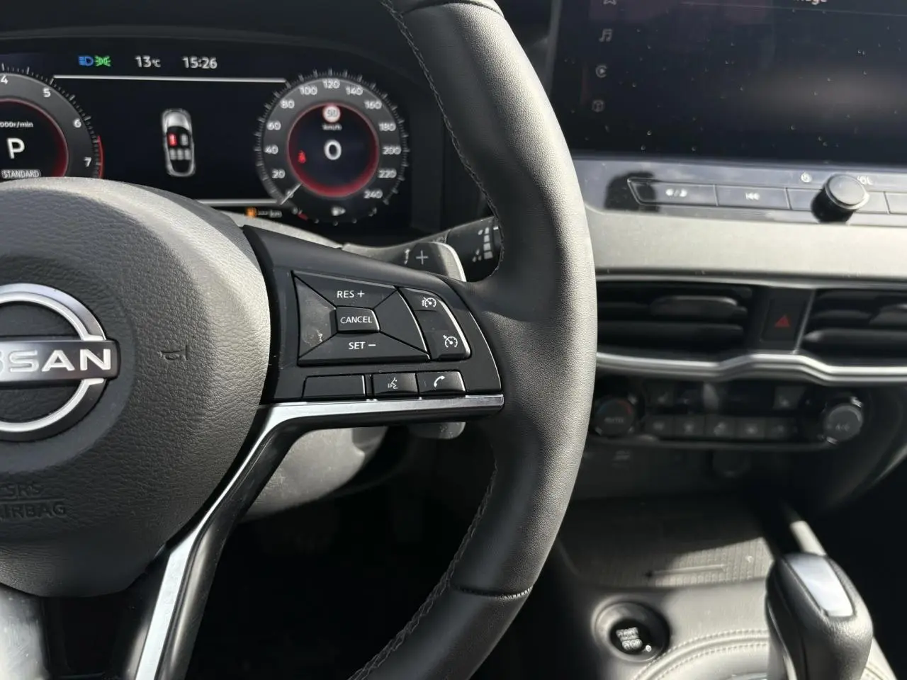 Vue rapprochée du volant noir et du tableau de bord numérique du Nissan Juke 2025 gris Ceramic.