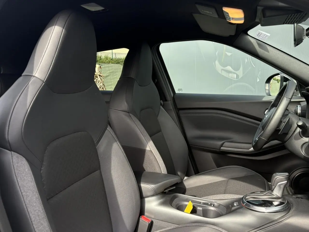 Vue intérieure côté droit du Nissan Juke 2025 gris Ceramic, montrant les sièges avant et la console centrale avec levier de vitesse.