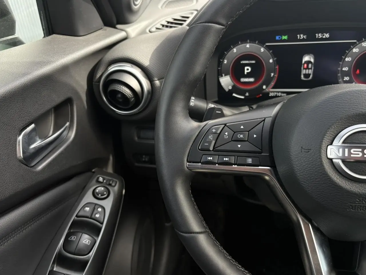 Vue intérieure côté conducteur du tableau de bord et volant noir du Nissan Juke 2025 avec commandes au volant visibles.