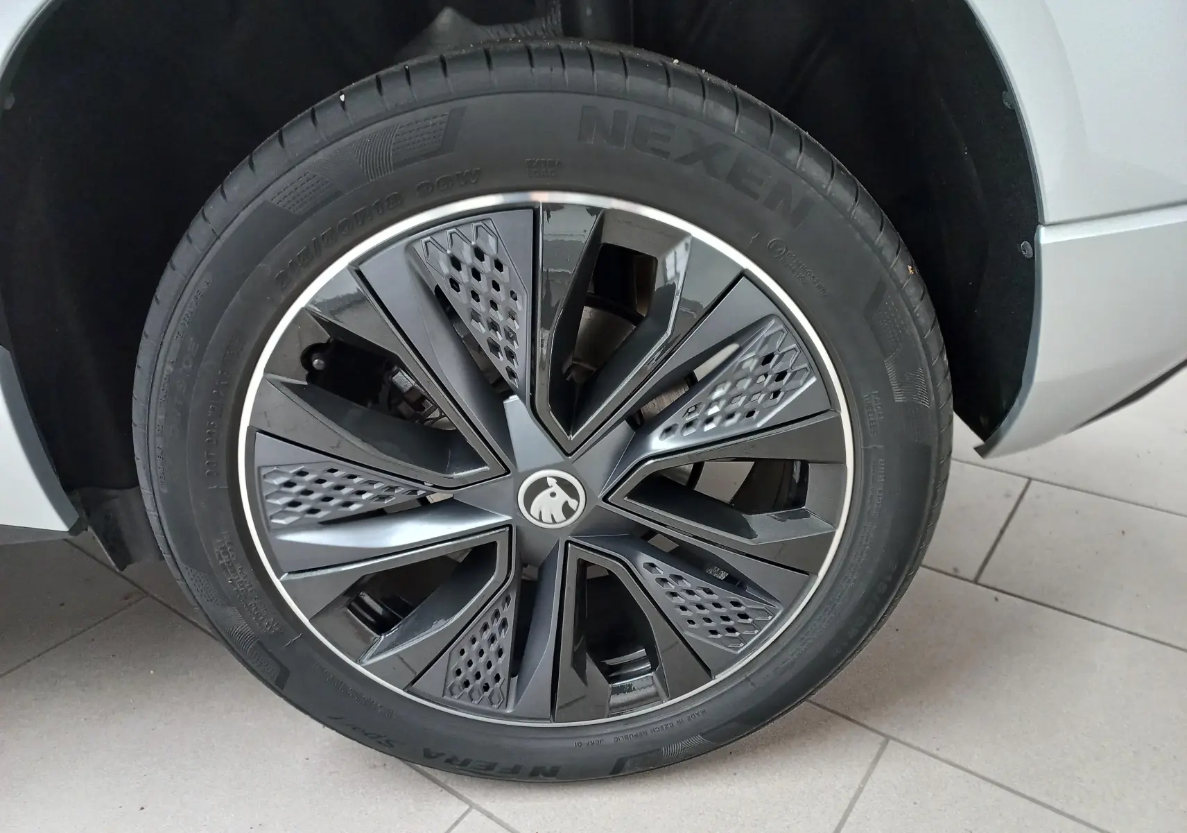 Gros plan sur la roue avant droite du Skoda Karoq gris argent, mettant en valeur la jante au design moderne et le pneu Nexen.