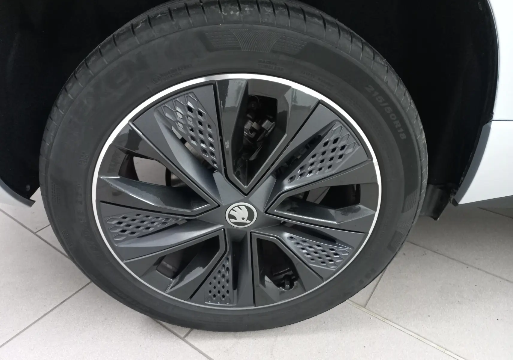 Gros plan sur la roue avant droite du Skoda Karoq gris argent, mettant en valeur la jante noire au design moderne.