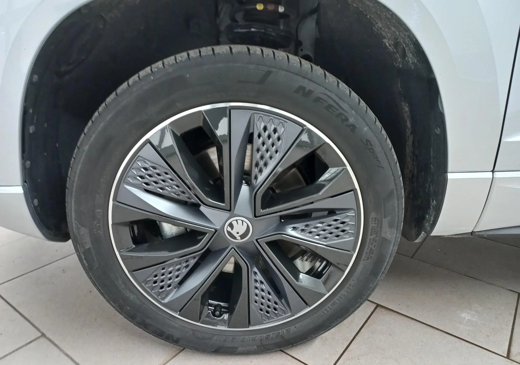 Gros plan sur la roue avant gauche du Skoda Karoq gris argent, mettant en valeur la jante au design moderne et sportif.